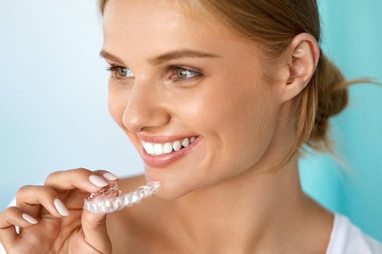Teeth Whitening. Beautiful Smiling Woman With White Smile, Straight Teeth Using Teeth Whitening Tray. Girl Holding Invisible Braces, Teeth Trainer. Dental Treatment Concept. High Resolution Image